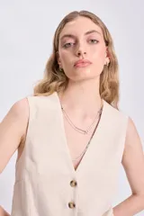 Chaleco corto color crudo de lino twill, con escote en V y cierre frontal con botones.