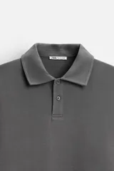 Polo manga larga gris con cuello solapa y cierre frontal de botonadura.