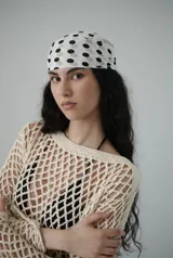 Top de manga larga color beige claro, tejido a crochet con patrón de red abierta. Tiene escote barco y corte corto.