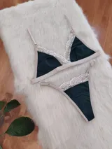 Conjunto de lencería de algodón color verde inglés con detalles de encaje nude, compuesto por un bralette de corte triangular con breteles regulables y una tanga con laterales ajustables.