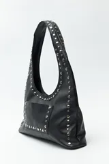 Cartera negra tipo hobo de cuero sintético con apliques de tachas metálicas plateadas en el frente y los bordes.