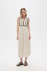 Vestido largo color crema con rayas verticales finas en negro, escote en V con ribete negro y corte holgado.