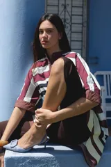 Camisa negra de algodón con cuello mao y mangas cortas. Presenta un pequeño bordado de una flor blanca en el pecho.