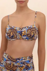 Top de bikini estilo bandeau con estampado abstracto en tonos azul, marrón y amarillo. Presenta breteles delgados, varilla interior y escote con frunces.