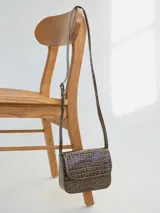 Cartera bandolera marrón con textura tipo piel de cocodrilo, correa larga ajustable y cierre con solapa.