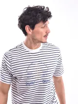 Remera blanca a rayas horizontales azul marino, con cuello redondo y estampado con texto en el pecho.