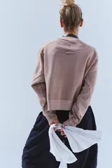 Buzo de tejido de punto color rosa pálido/beige, con largo ligeramente cropped y calce amplio tipo boxy. Presenta detalles de costuras visibles en toda la prenda.