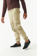 Pantalón cargo gris con puños elásticos, corte regular, bolsillos laterales con solapa y pasacintos.