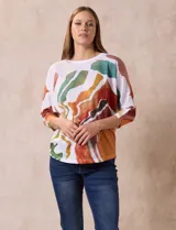 Buzo blanco con estampado abstracto en tonos naranja, verde, marrón y rojo. Tiene cuello redondo y mangas 3/4.