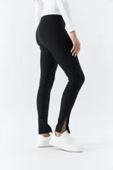 Pantalón negro de tiro alto, corte ajustado y aberturas en los tobillos.