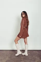 Minifalda acampanada de cuero color caramelo con costuras decorativas en hilo blanco.