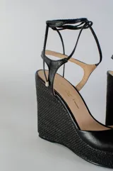 Sandalias negras de cuero con plataforma y tacón corrido de yute. Tiras finas de cuero que se atan al tobillo.