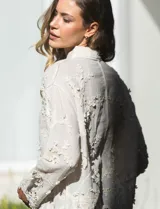 Camisa de algodón color crema, marca Liv Los Angeles, con bordado floral y terminaciones en crochet en puños y ruedo. Tiene cuello con solapa y abertura central con botones.
