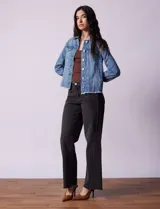 Campera de jean celeste de la marca Baccini, con cierre central, bolsillos delanteros, apliques colgantes de tachas en los hombros y terminación desflecada en el ruedo.