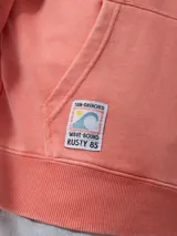 Canguro con capucha color salmón/coral desgastado, con efecto lavado. Presenta un estampado frontal con el texto "RUSTY & SUN" y un diseño de olas en color amarillo pálido. Tiene bolsillo canguro frontal y puños y cintura acanalados.