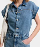 Mono corto de jean azul, con cuello camisero, cierre abotonado frontal, mangas cortas con dobladillo, trabillas en la cintura y bolsillos delanteros y traseros.