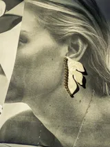Aros colgantes con forma de media flor color crema y detalle de strass dorados.