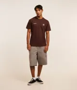 Remera marrón de algodón, corte clásico, con cuello redondo y manga corta. Presenta un pequeño estampado con lettering y un logo en el pecho.