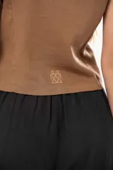 Chaleco marrón con escote en V, sin mangas y cierre frontal con botones.