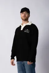 Sweater de punto verde con cuello polo color crema y bordado frontal con texto en blanco.