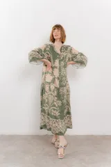 Vestido largo azul con estampado floral en tonos beige, confeccionado en viscosa. Presenta escote en V, botonadura completa en el frente y mangas largas con volados.