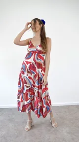 Vestido midi con estampado abstracto en tonos rojo, azul y marrón, con breteles finos y corte escalonado.