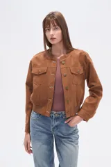 Campera estilo bomber corta de gamuza color marrón, con cuello redondo, cierre frontal de botones y dos bolsillos de parche con solapa en el pecho. Presenta puños y cintura elásticos.