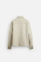 Sobrecamisa color beige de corte recto, con cuello solapa, manga larga con puños abotonados, cierre frontal abotonado, bolsillos de parche con solapa en el pecho y bolsillos de ojal en la cadera.