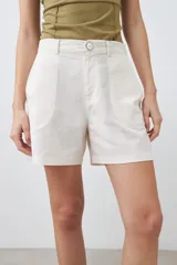 Short color beige claro, de tiro alto, con bolsillos laterales y cierre frontal con botón.