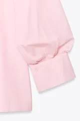 Camisa rosada de popelina de algodón, con cuello clásico, manga corta abullonada y cierre frontal con botones.