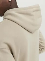 Canguro color beige con capucha y cordones ajustables, de manga larga y bolsillo tipo canguro.