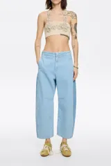 Pantalón vaquero de corte barrel, largo tobillero, tiro medio, con cierre frontal de botón y cremallera, bolsillos delanteros en costura, bolsillos de plastrón en la parte posterior y costadillos laterales.
