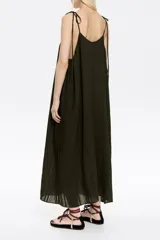 Vestido midi verde oscuro de corte amplio, con breteles finos que se atan en los hombros.