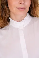 Camisa negra de viscosa con cuello alto y volados en cuello y puños. Cierre frontal con botones de nácar.