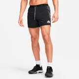 Short deportivo negro con logo Nike Trail estampado en blanco, cintura elástica con cordón ajustable y paneles laterales en gris.