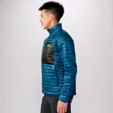 Campera con cierre frontal, color azul con bolsillo negro en el pecho, de la marca Mountain Hardwear. Rellena con poliéster reciclado, ultraliviana y compactable. Ideal para actividades al aire libre como mochileros, escalada, senderismo, viajes y acampada.