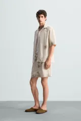 Bermuda regular fit color beige con bordados de flores en tono marrón. Tiene cintura elástica ajustable con cordón, bolsillos laterales y un bolsillo trasero de plastrón.