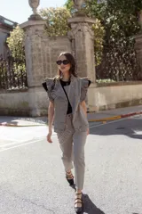 Jean gris lavado, estilo mom fit, con aplique fruncido en forma de espiral en la pierna izquierda, tiro alto, bolsillos delanteros y traseros funcionales, y cierre frontal con botón y cremallera.