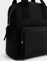 Mochila negra de cuerina con doble asa corta de mano con textura, correas regulables, cierre superior, bolsillo frontal con cierre, bolsillos laterales y tag en relieve.