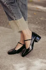 Zapatos de charol negro con diseño tipo T-bar, taco bajo cuadrado y punta redondeada.