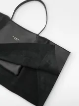 Bolso negro de piel bovina con doble capa con caída y godets laterales. Tiene asa corta de hombro y logo grabado.