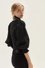 Top negro de calce al cuerpo con escote cuadrado amplio. Mangas largas abullonadas con puños elastizados.