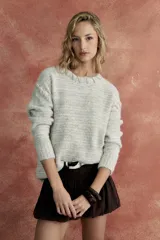 Sweater tejido color gris melange, de corte holgado y cuello redondo, con bordado crudo en cuello y hombros.