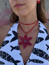 Collar con cordón fucsia y dije en forma de flor rosa con detalles de mostacillas de colores.