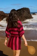 Remera tipo polo a rayas horizontales color borgoña y fucsia, con cuello clásico color crema, mangas largas abullonadas con puños elásticos y botones de nácar.