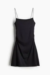 Vestido corto negro de breteles finos, escote cuadrado, corte ajustado y frunces laterales que generan un efecto drapeado en la falda.