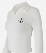 Blusa de manga larga color crema, con cuello polo, escote en V y bordado de ancla en el pecho.