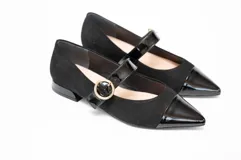 Zapato guillermina de gamuza negra con puntera de charol brillante y tira sobre el empeine con hebilla dorada. Tacón bajo y cuadrado.