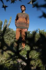 Buzo tejido con cuello redondo, mangas largas y diseño con motivos geométricos en tonos marrón, naranja y verde.