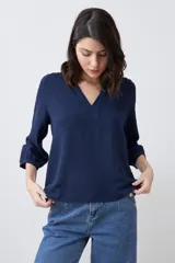 Blusa color crudo con escote en V y mangas largas.